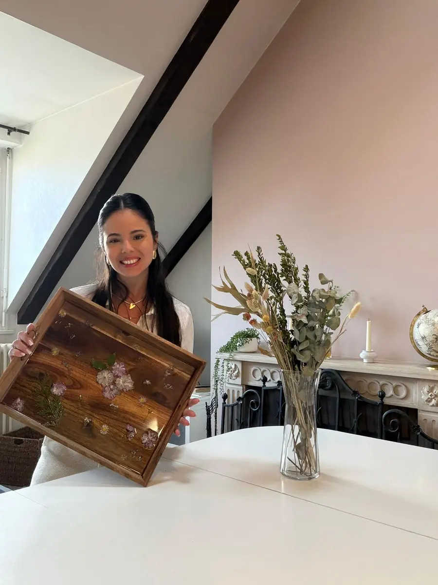 Amanda Berton souriante, tenant un plateau garni de fleurs pressées