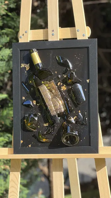 Bouteille de vin éclatée et reconstituée dans la résine avec de la feuille d'or, encadrée en noir