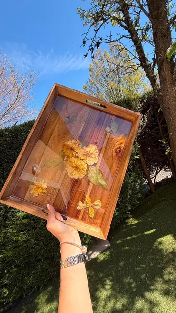 Plateau rectangulaire tenu à la main avec des fleurs orange, contre le ciel