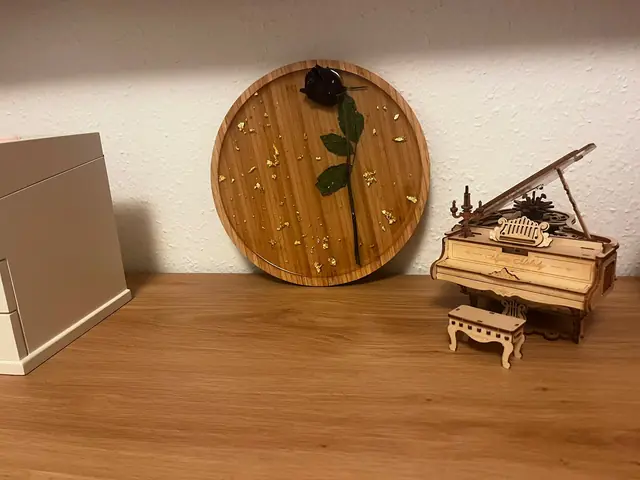 Plateau rond avec une rose foncée et de la feuille d'or dans la résine